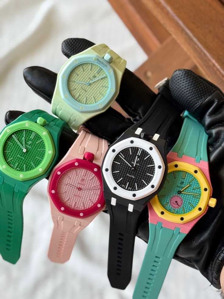 Collection de Royal Pop avec bracelets de différentes couleurs portées sur une main, présentant des bracelets compatibles pour transformer une Royal Pop en montre de poignet personnalisée.